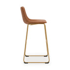 Tall upholstered barstool, tan upholstery, gold frame with footrest and curved back profile.