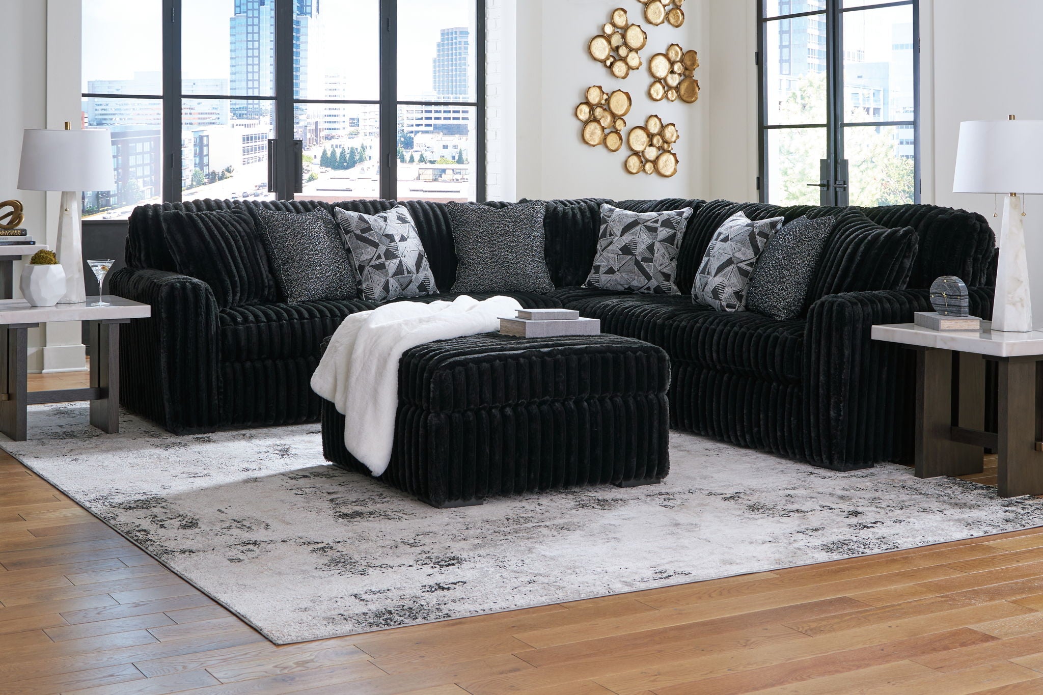 Black sectional sofa with chaise and ottoman cube, shown with lumbar pillows