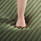 Green corduroy sofa seat with foot resting on the cushion