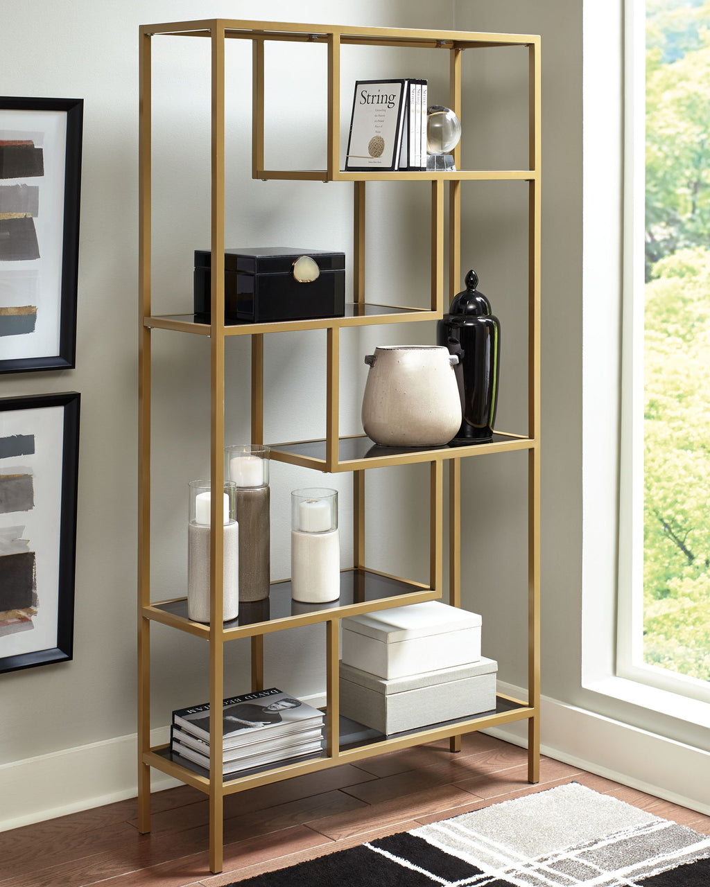 Gold bookcase with open shelves holding books, jars, and small decor items