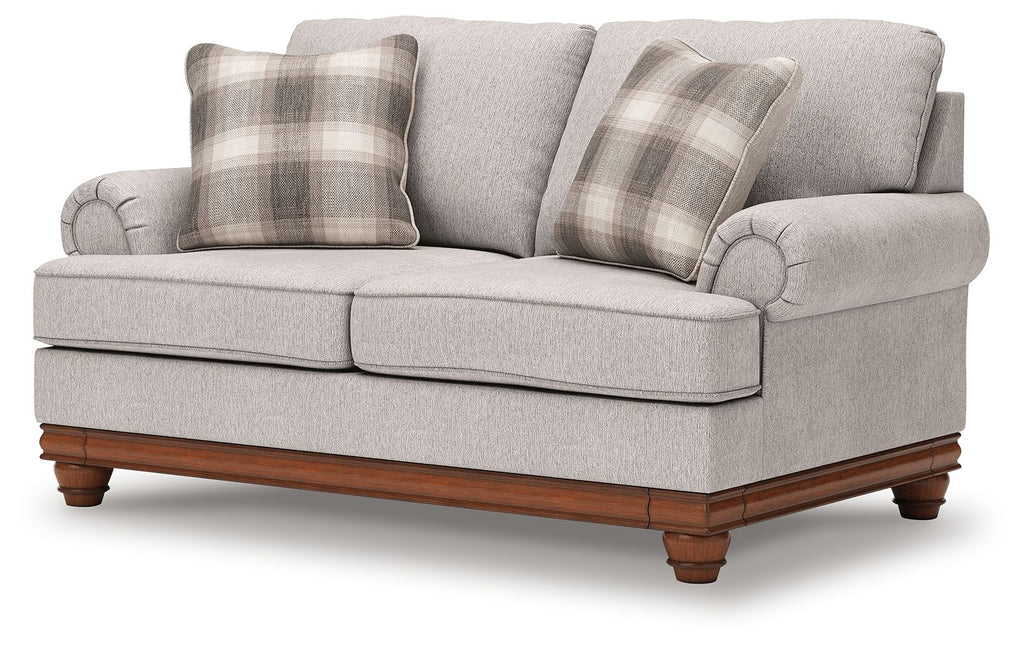 Upholstered loveseat in light sand fabric with plaid throw pillows and rolled arms
