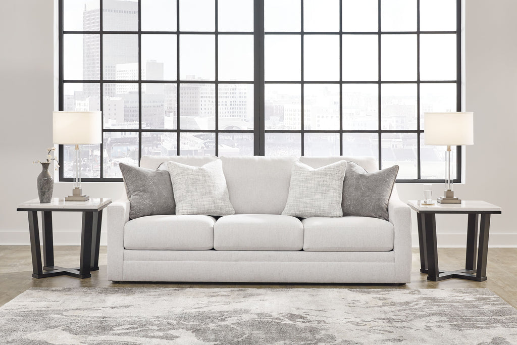 Light gray sofa with three seat cushions and several gray throw pillows