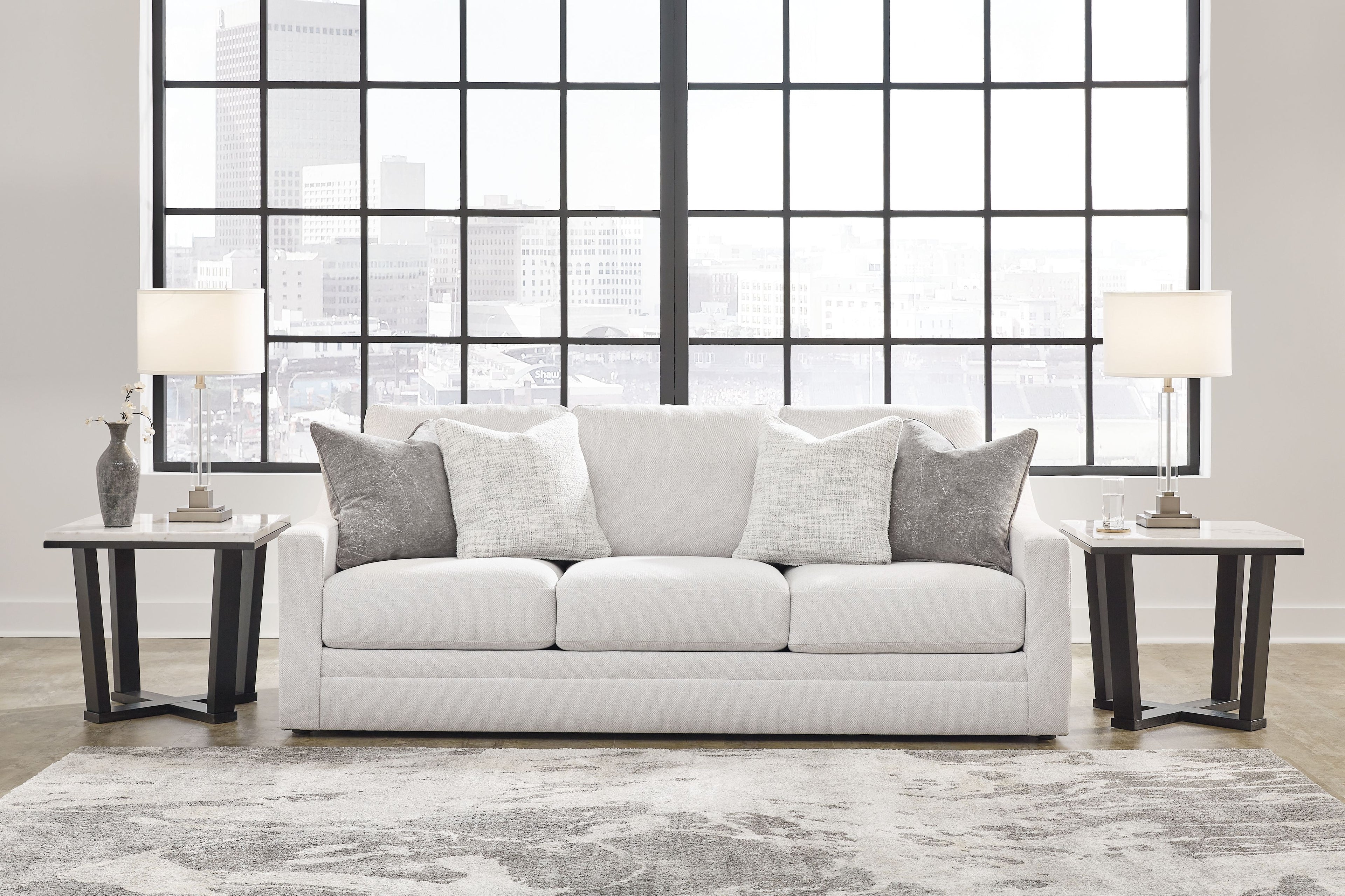 Light gray sofa with three seat cushions and several gray throw pillows