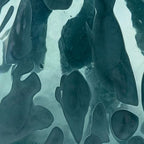 Close-up of blue glass vase with glossy abstract shapes and speckled texture