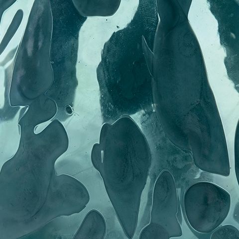 Close-up of blue glass vase with glossy abstract shapes and speckled texture