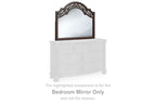 Arched brown bedroom mirror on white dresser with ornate carved frame