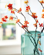 Teal glass vase with orange and yellow blossoms on dark stems