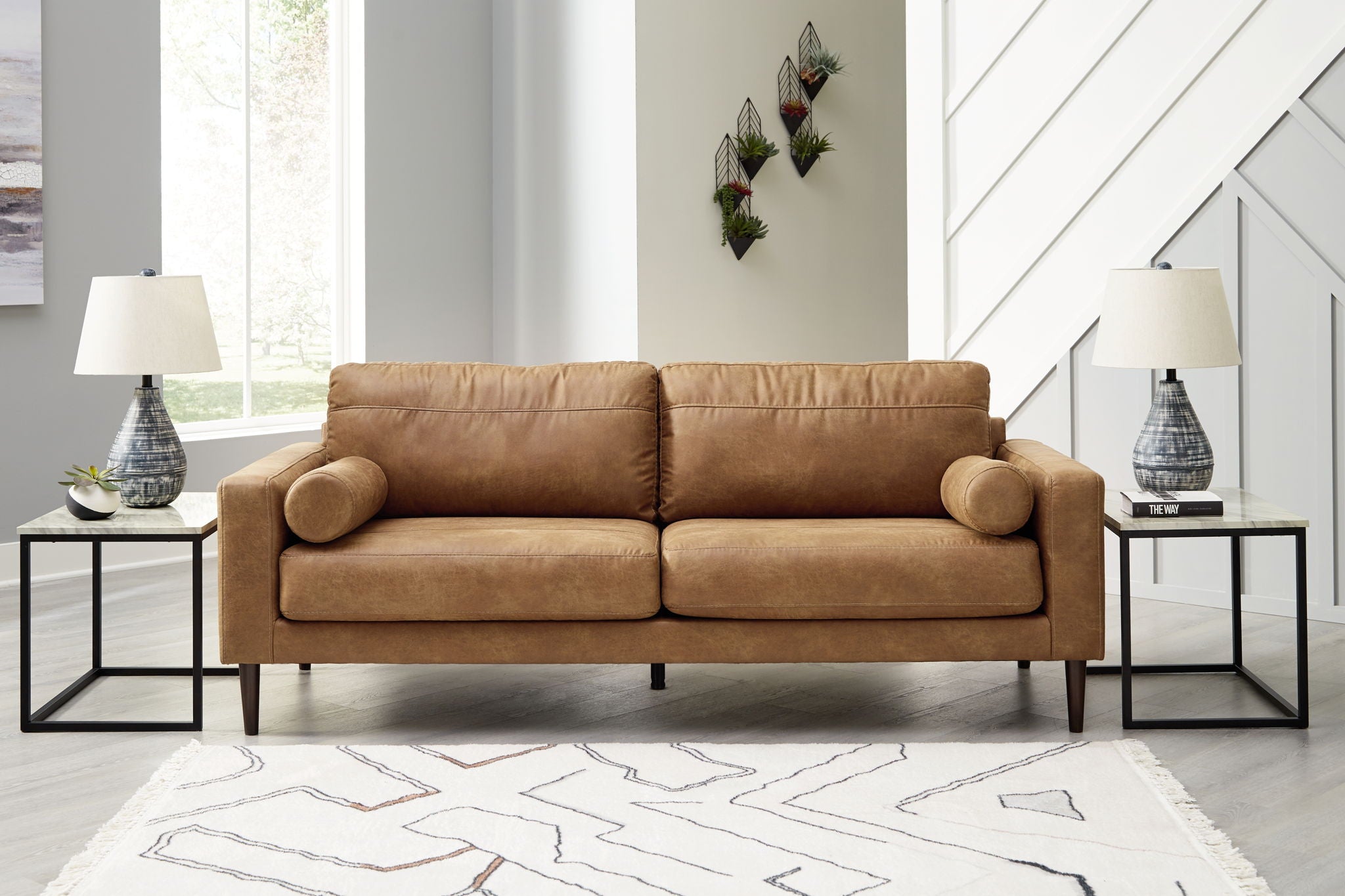 Light brown upholstered sofa with rounded arms, bolster back cushions, and tapered legs
