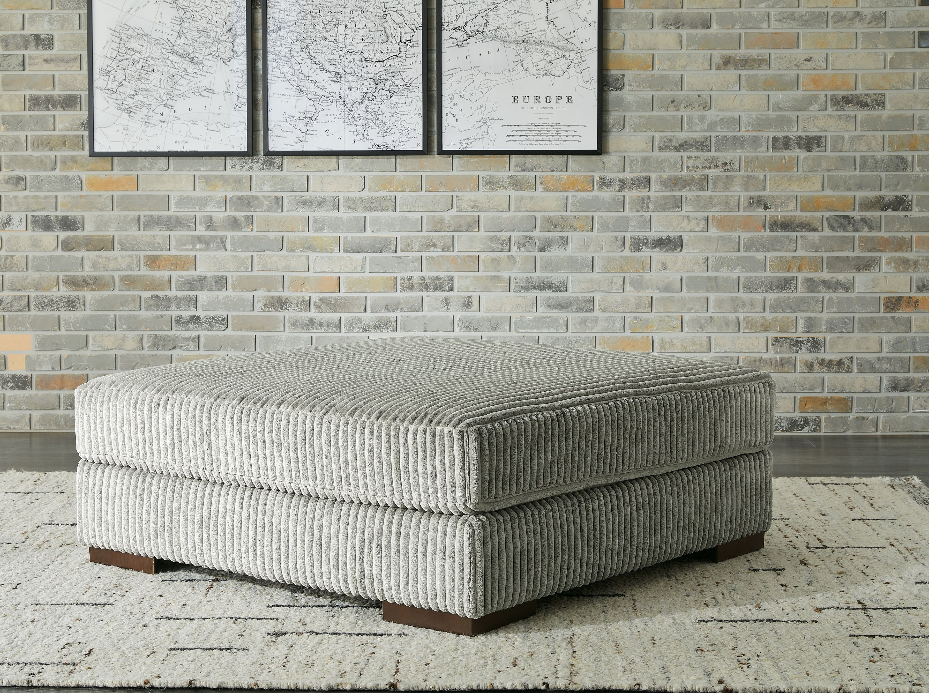 Gray oversized ottoman with ribbed fabric upholstery and square cushioned top