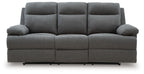Dark gray reclining sofa with three seat sections and tufted back cushions