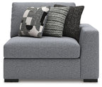 Gray corner accent chair with supportive armrests and two patterned decorative pillows