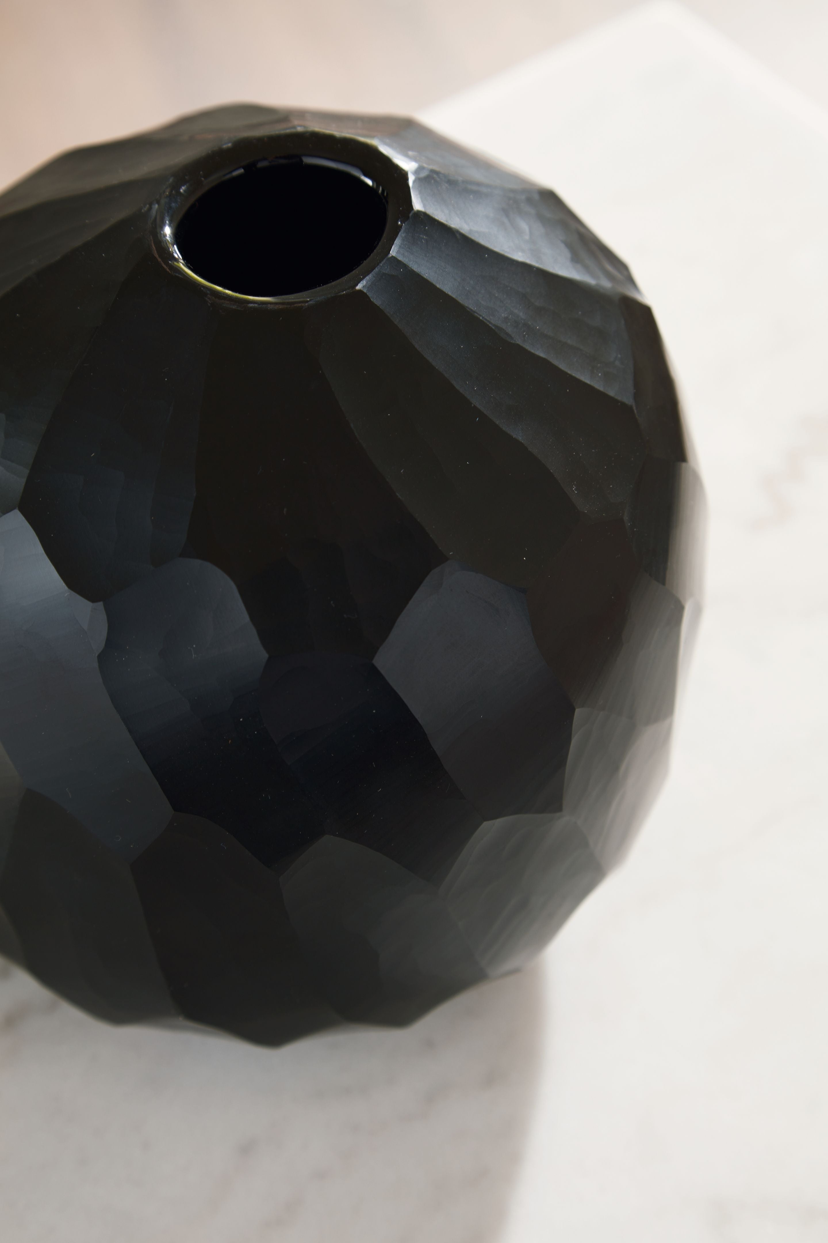 Black faceted vase with open neck and textured surface detail