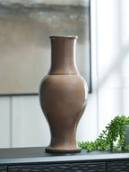 Brown ceramic vase with flared base, standing on a tabletop