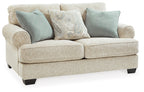Sandstone loveseat angled view with teal accent pillows, patterned center cushion, and dark legs