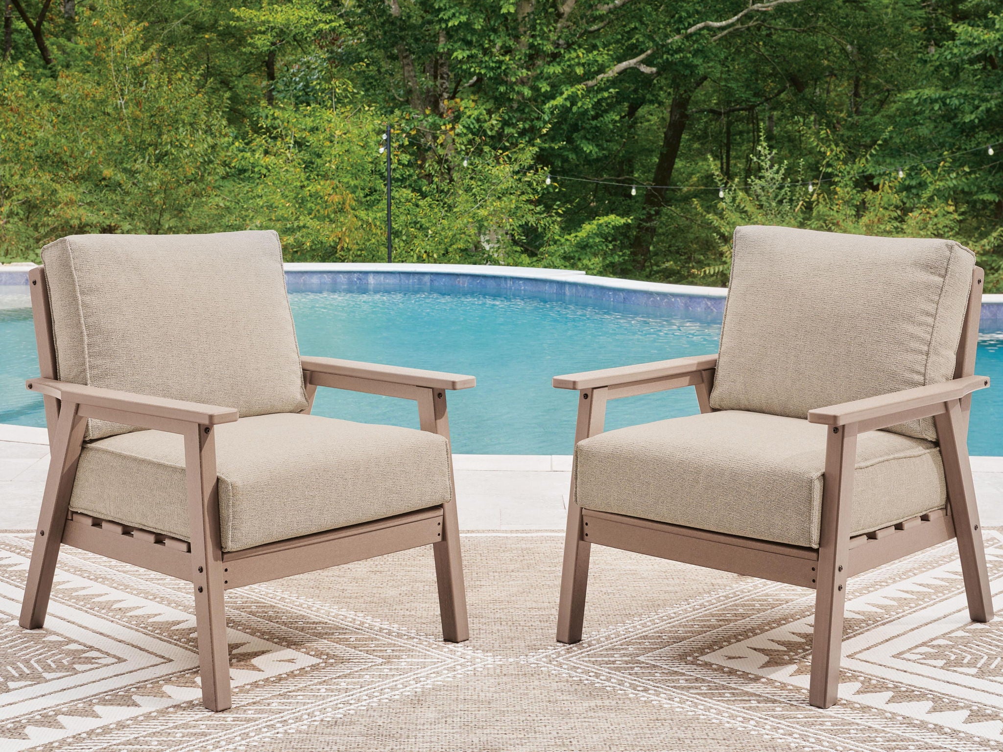 Two lounge chairs with beige cushions, light driftwood frames, and slatted armrests