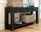 Black sofa table with four drawers and open lower shelf with bin and bottle