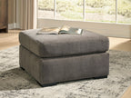 Gray upholstered accent ottoman with square silhouette, cushioned top, and block legs