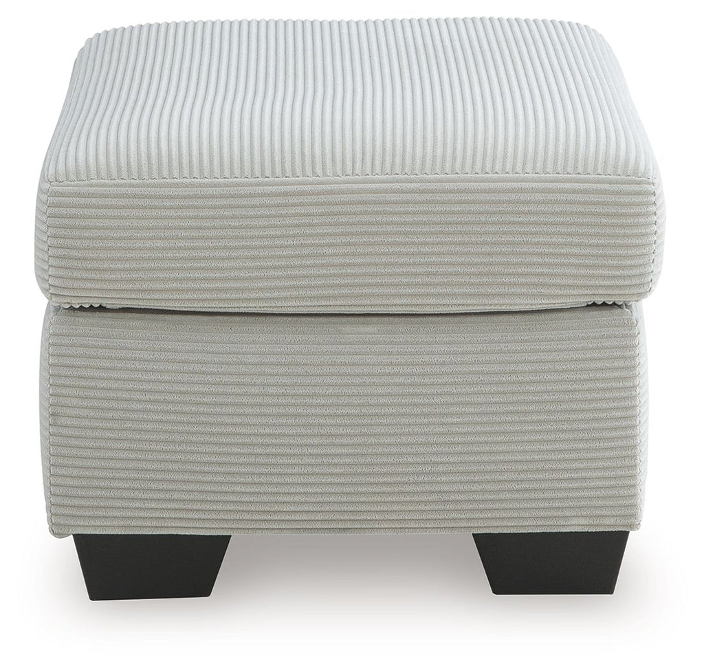 Light gray upholstered ottoman with ribbed fabric and visible seam across the lid