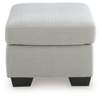 Light gray upholstered ottoman with ribbed fabric and visible seam across the lid