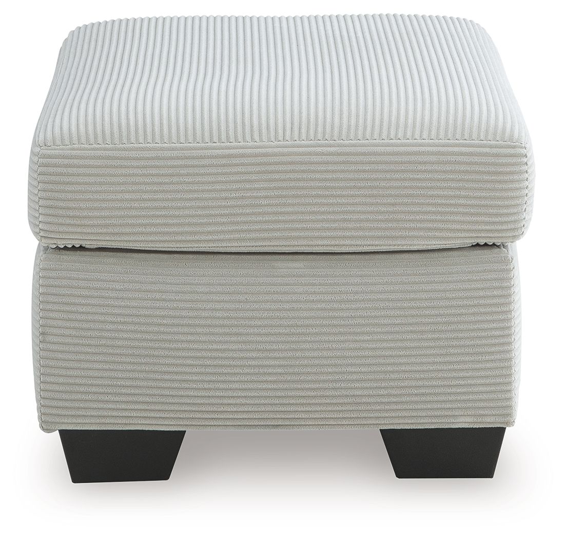 Light gray upholstered ottoman with ribbed fabric and visible seam across the lid