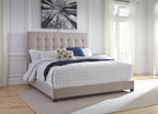 Dolante upholstered bed with beige tufted headboard, white quilt, blue pillow, dark throw