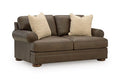 Dark brown loveseat with two patterned throw pillows, rounded arms, and wooden legs
