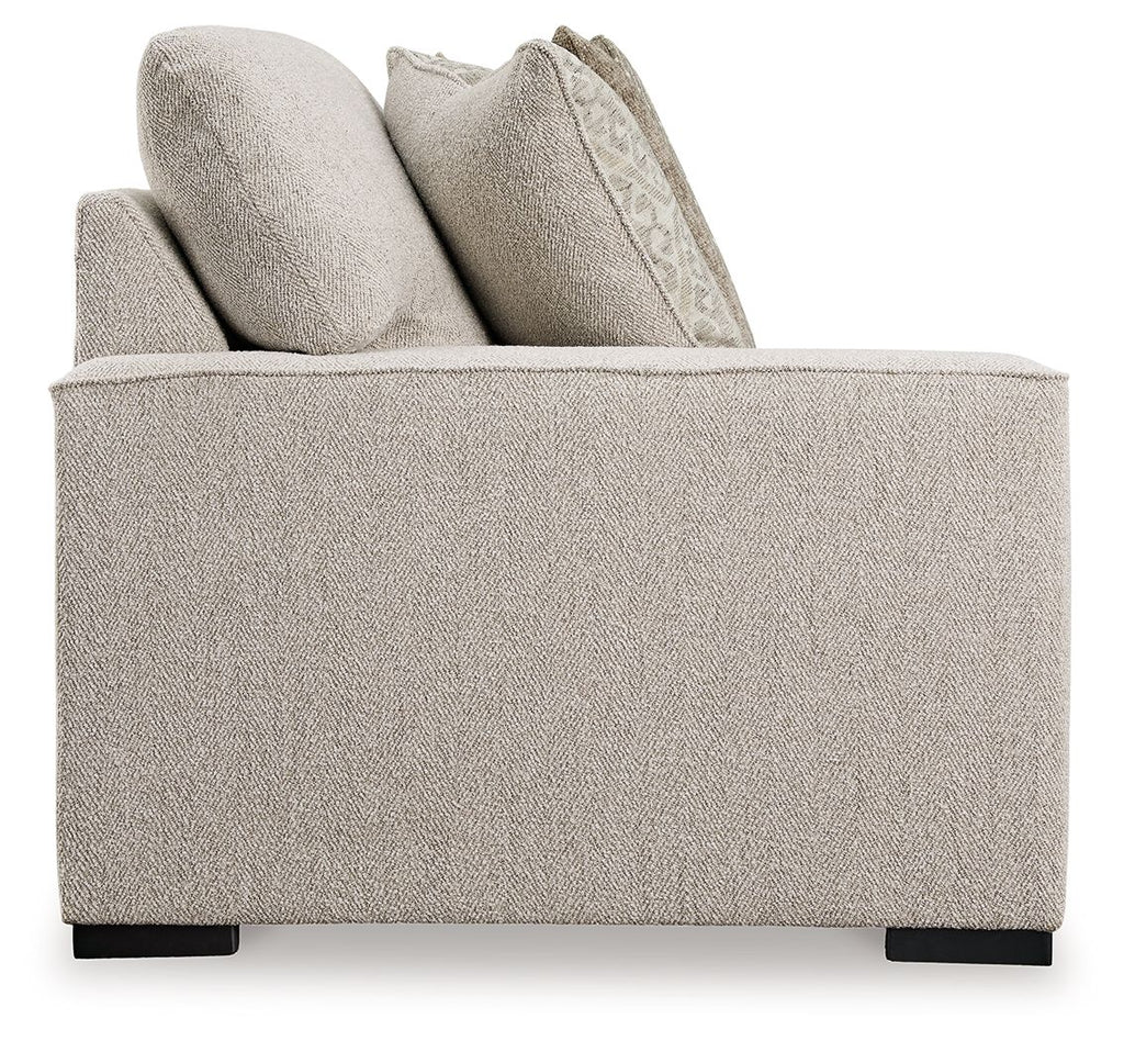 Sand-tone upholstered loveseat arm with two throw pillows and black block feet