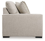 Sand-tone upholstered loveseat arm with two throw pillows and black block feet