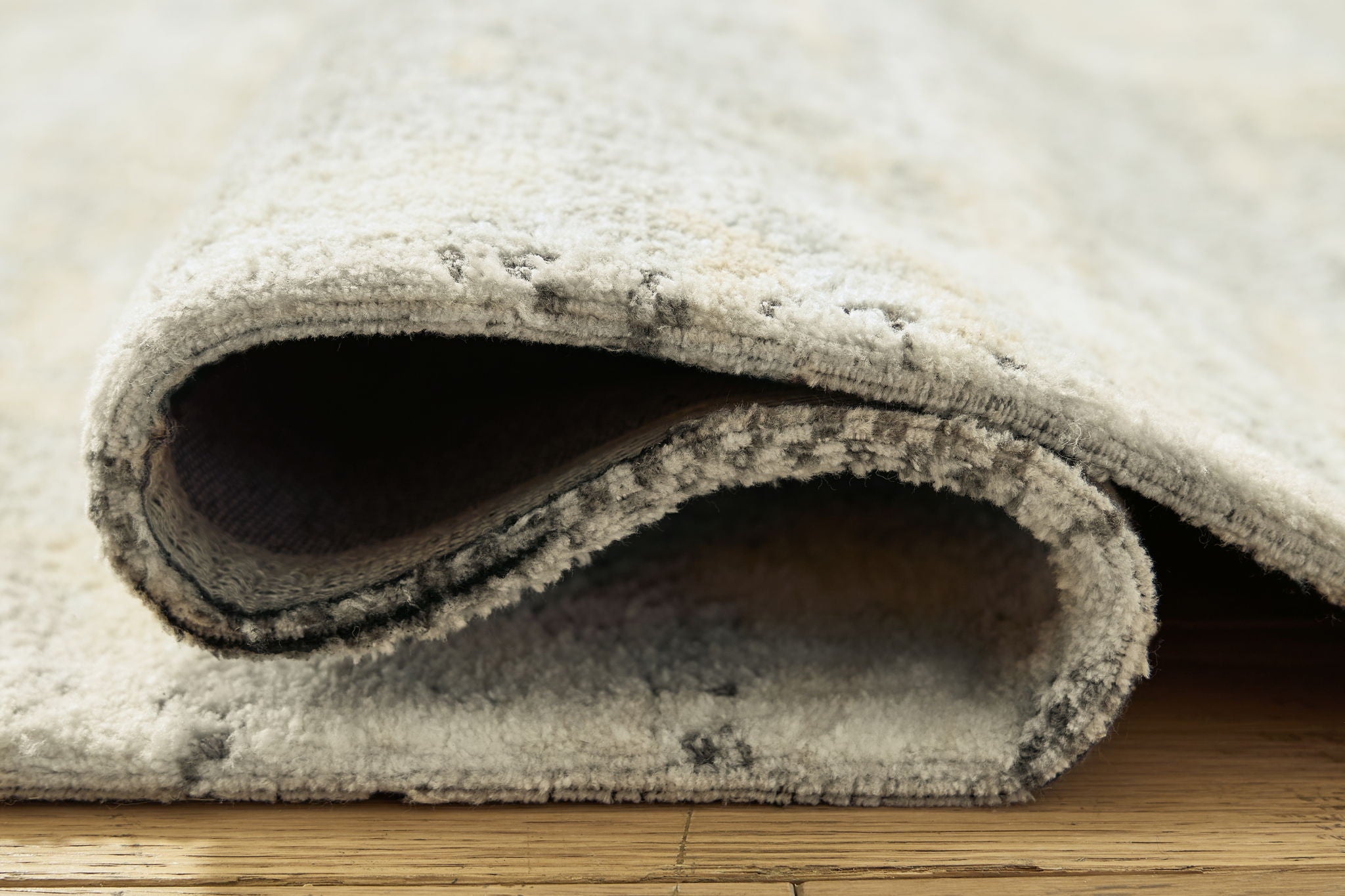 Close-up of rug backing fold showing underside of cream and gray pile