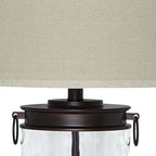 Bronze-finish hardware on clear glass table lamp with beige drum shade