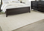 Cream rug laid flat with subtle wavy line design and low, textured pile
