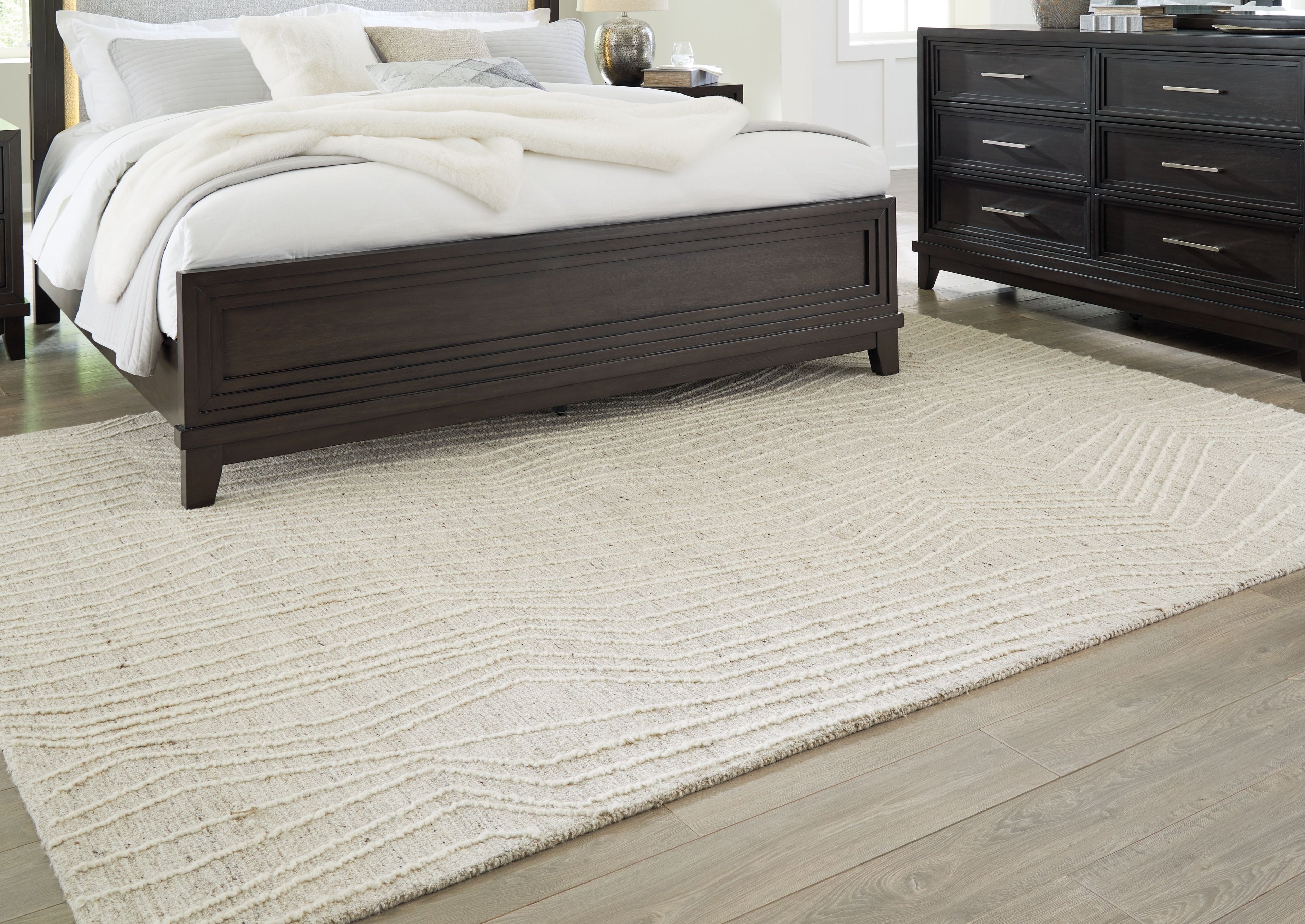 Cream rug laid flat with subtle wavy line design and low, textured pile