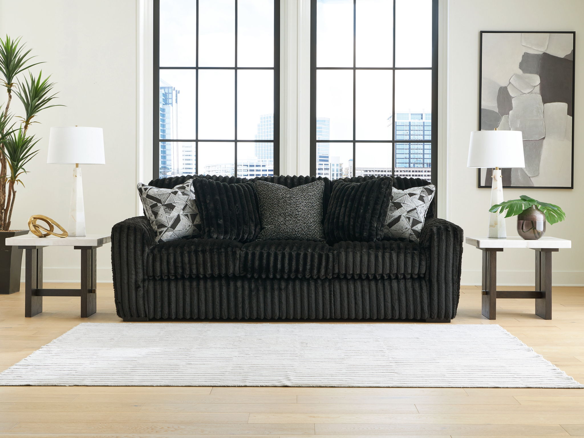 Dark corduroy loveseat with two patterned throw pillows and a solid center back cushion.