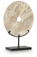 Light beige circular sculpture with drilled hole on dark metal stand base