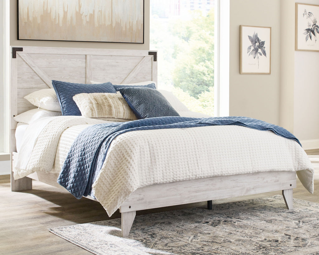 Panel bed with whitewashed wood frame and paneled headboard, white bedding with blue covers