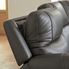 Dark gray reclining chair with thick padded arm, curved headrest, and stitched seams
