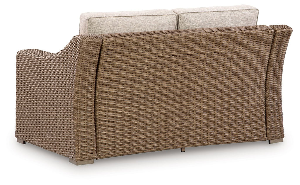 Beige loveseat seat cushion on brown woven wicker frame, side view