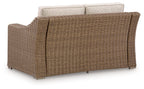 Beige loveseat seat cushion on brown woven wicker frame, side view