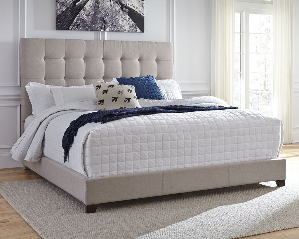 Dolante upholstered bed with beige tufted headboard, white quilt and blue accent pillows