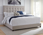 Dolante upholstered bed with beige tufted headboard, white quilt and blue accent pillows
