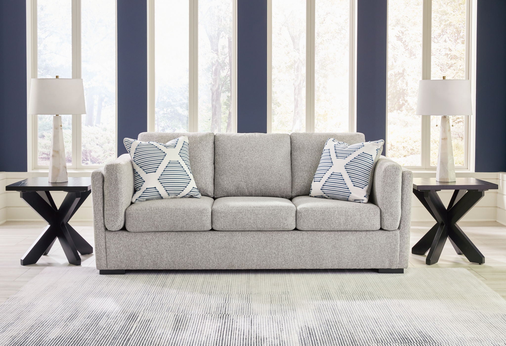Gray living room sofa set with two patterned throw pillows and matching armchair ottoman