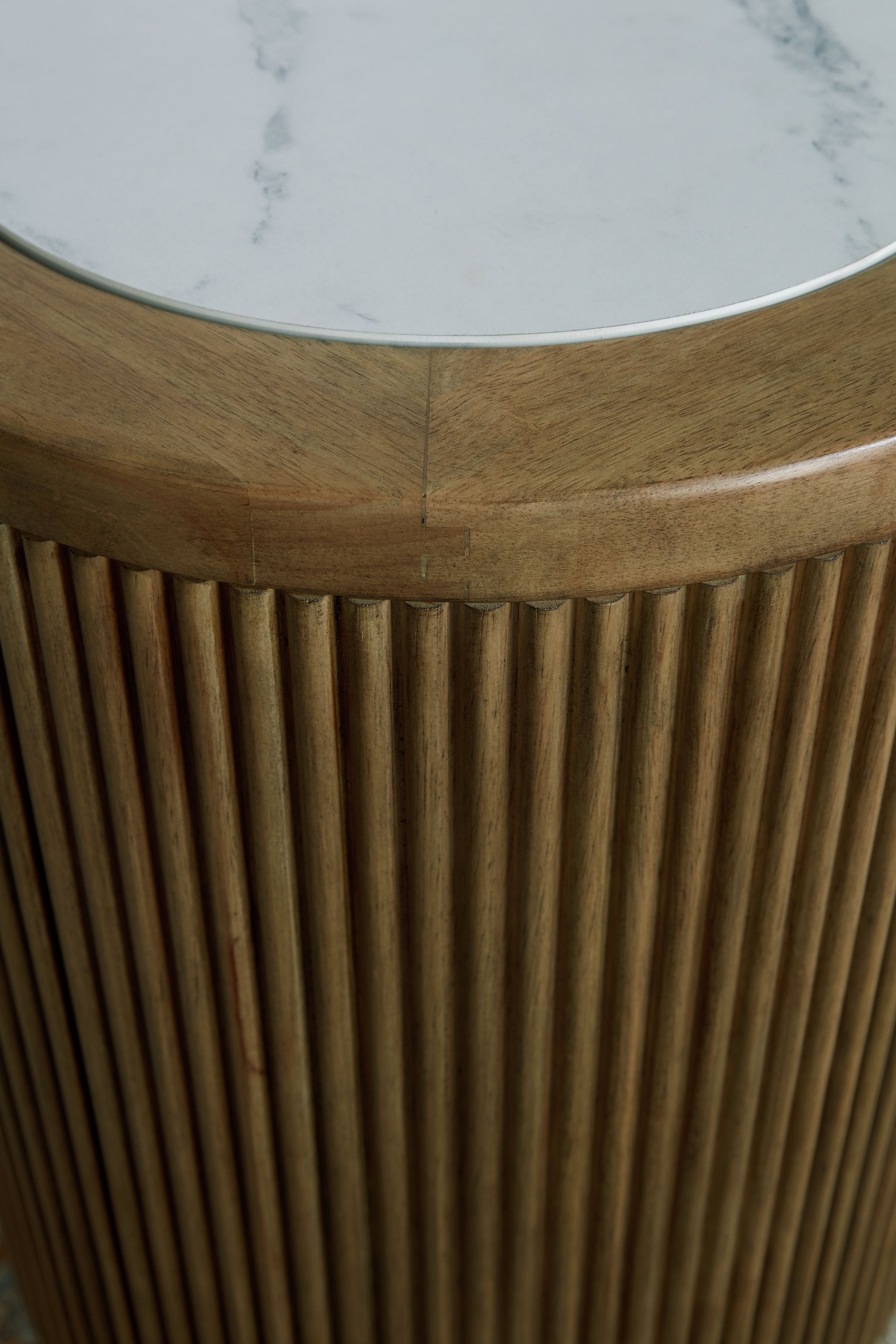 Round end table side detail: light brown fluted wood with white stone edge