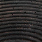 Dark vase surface detail showing tight horizontal grooves and speckles