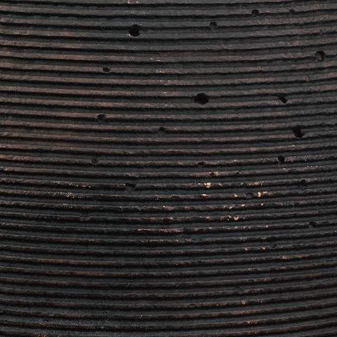 Dark vase surface detail showing tight horizontal grooves and speckles