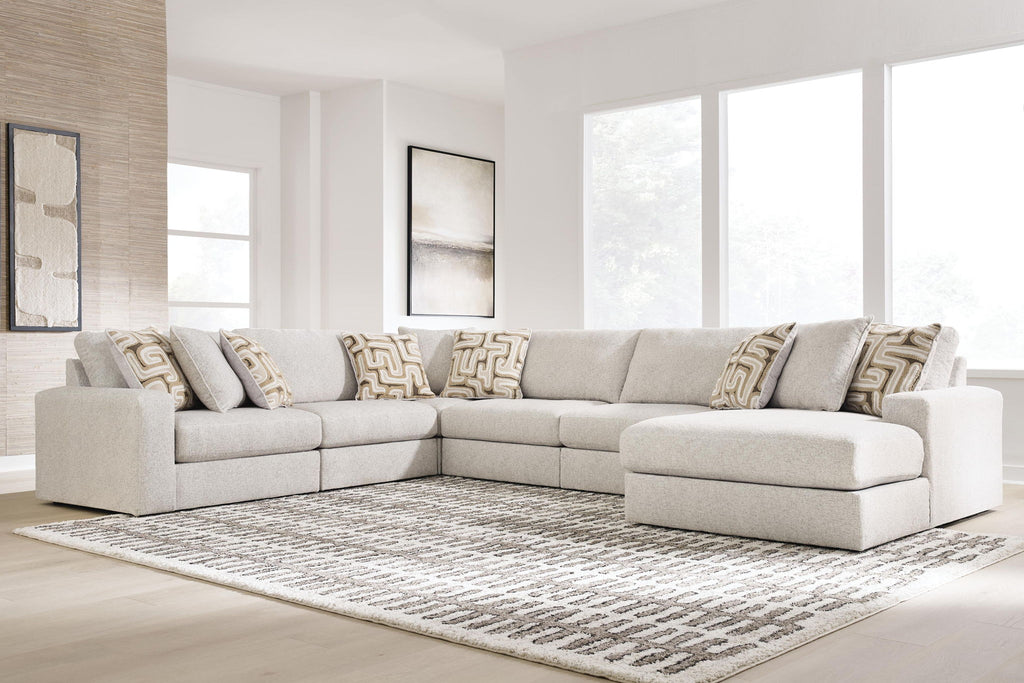 Light beige sectional sofa with corner chaise and patterned throw pillows.