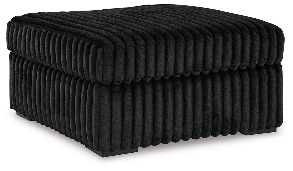 Black ottoman with ribbed, tufted upholstery and rounded corners