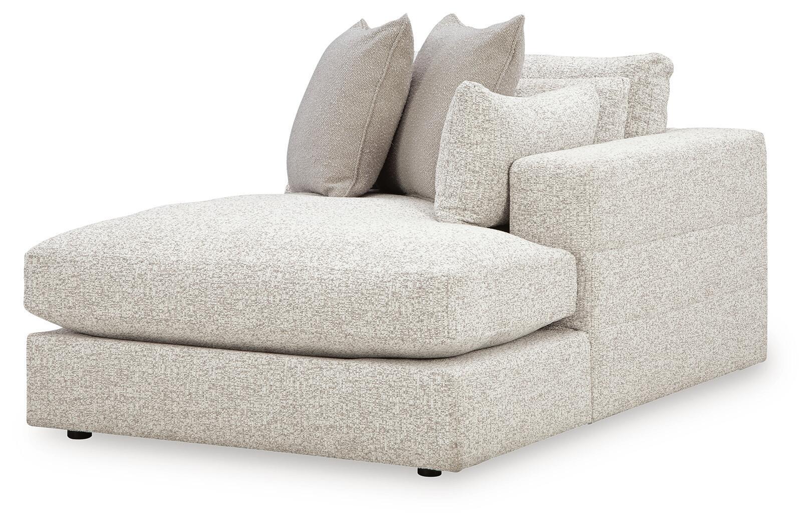 Corner chaise ottoman with light beige upholstery and stacked back pillows, rounded end