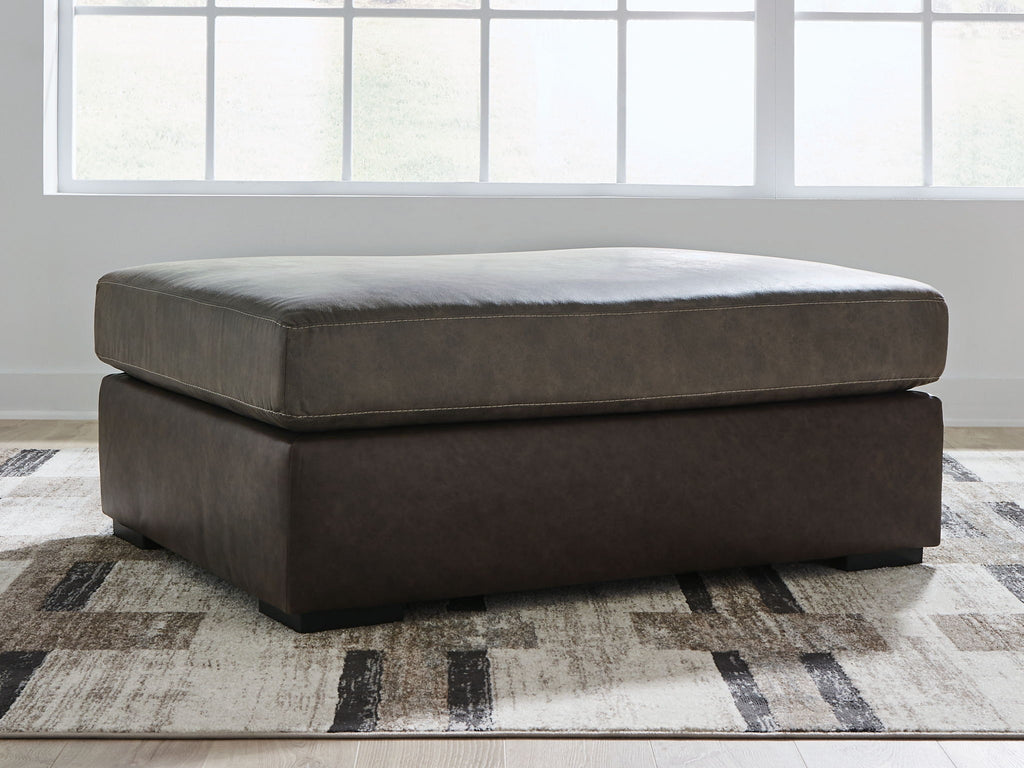 Oversized accent ottoman in dark brown upholstery with square top and low profile.