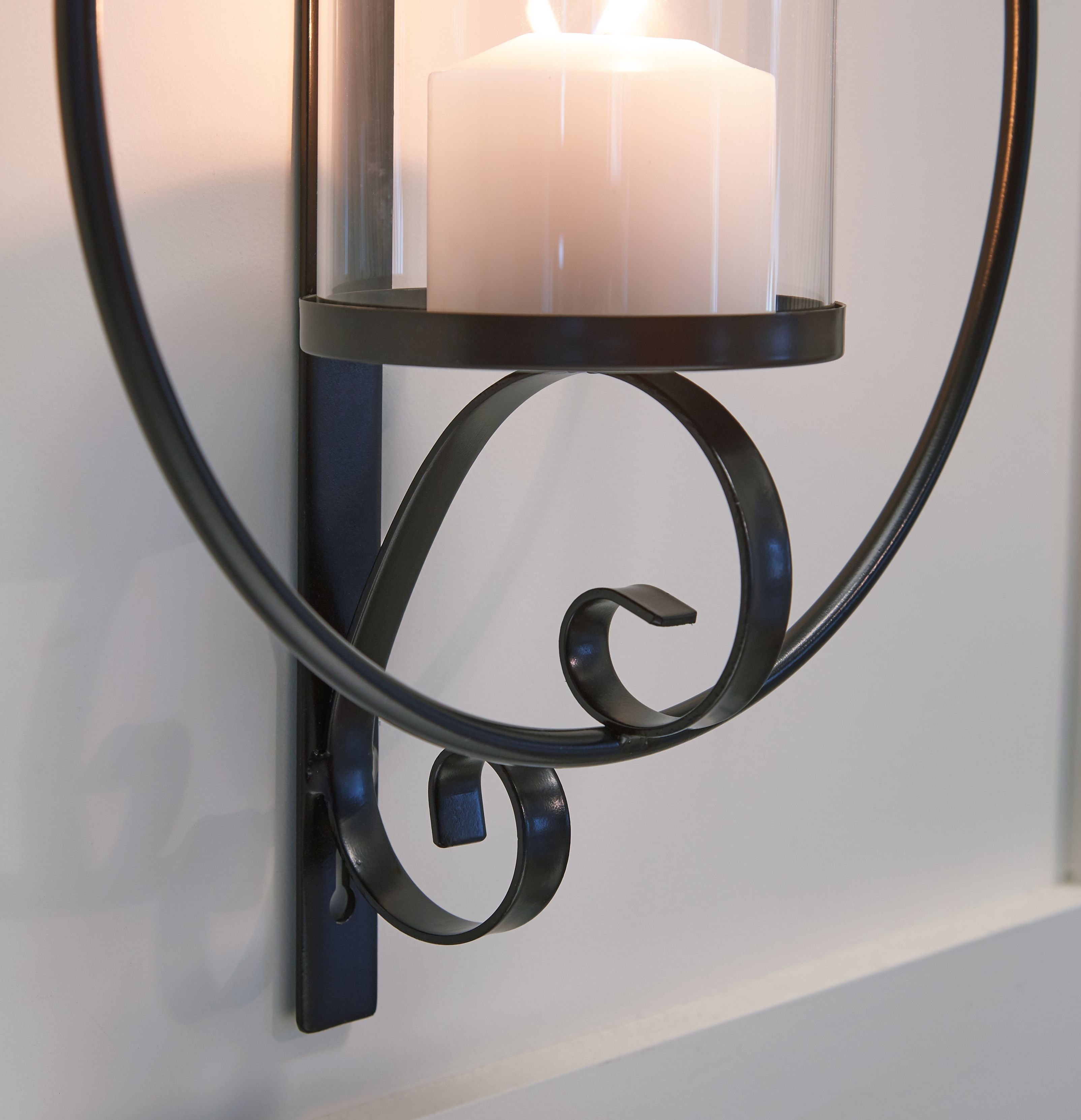 Black wall sconce with curved metal ring and clear glass cylinder shade