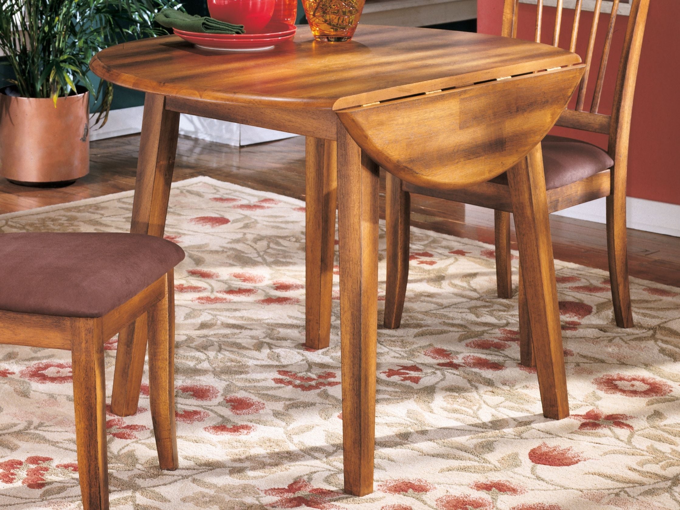 Round rustic brown drop-leaf table with hinged leaf section on tabletop